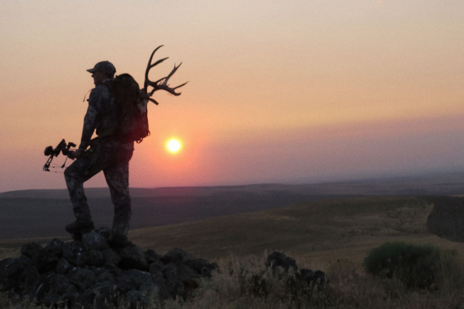 Bowhunter on the rimrock at sunset